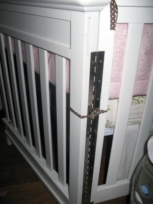 View of a hinge added to allow the crib's side to swing out to open.