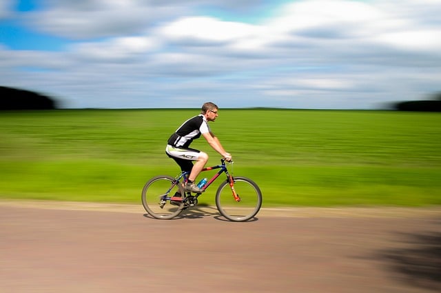 A fit man wearing cycling clothes and riding a bike in a rural setting.