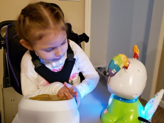 Une jeune fille activant un jouet adapté à un interrupteur.