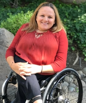 Une femme souriante assise dans un fauteuil roulant en plein air