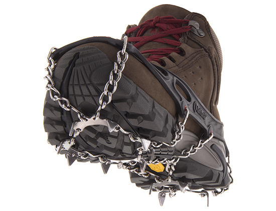 A hiking boot with metal crampon spikes stretched across the sole.