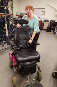 Una mujer en un almacén se inclina sobre una silla de ruedas eléctrica.