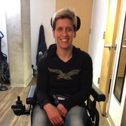 A woman seated in a power wheelchair smiling.