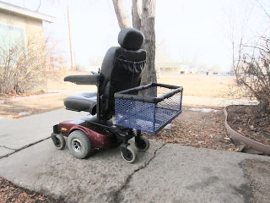Una silla de ruedas eléctrica con una cesta montada en el respaldo.