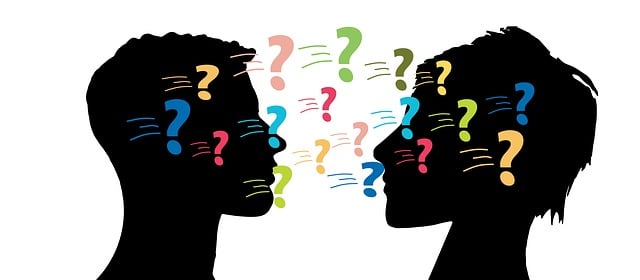 Profile silhouettes of a man and woman's heads facing each other with question marks between them.