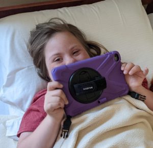 A girl using an iPad in bed.