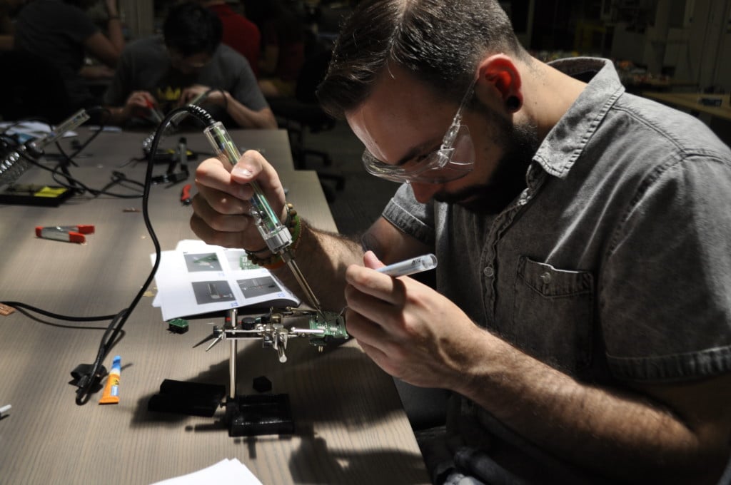 Man wearing protective eye-wear works with tools intently.