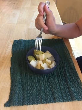 A bowl of fruit on a nonskid place mat.