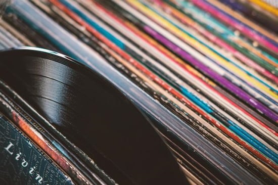 Close up of a stack of vinyl record album covers with one record emerging.