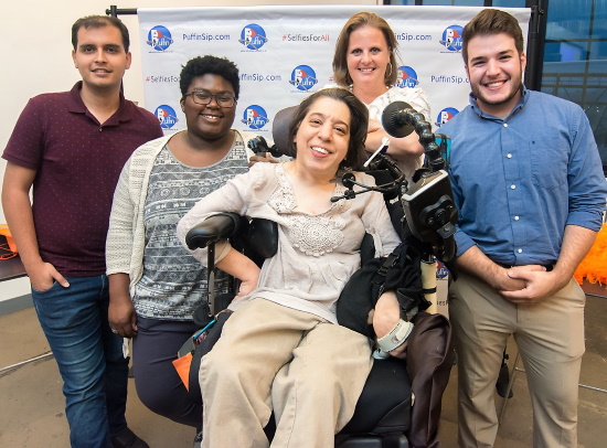 A smiling woman in her power wheelchair with two men and two women standing smiling with her.