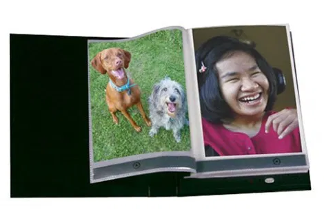 A photo album open displaying a picture of dogs and a picture of a girl.