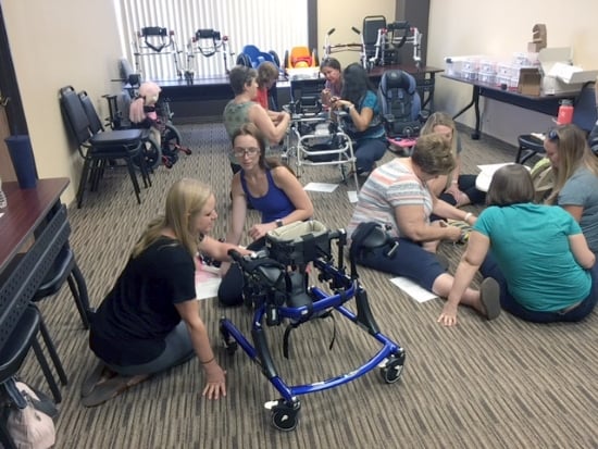 Women working in groups on the floor with pediatric mobility equipment.