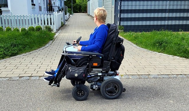 A woman traveling in a power wheelchair on pavement in a residential community.