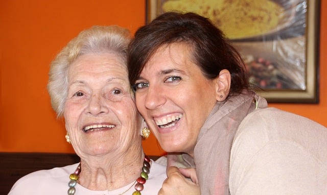 Head-shot of two women smiling for a selfie, embracing; one is elderly.